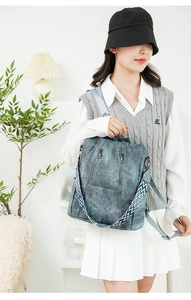 Detail of blue-grey matte backpack showing vertical metal zippers and wide woven strap