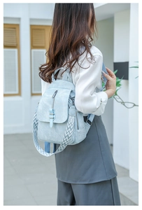 Light blue PU leather backpack with wavy strap detail shown on a female model