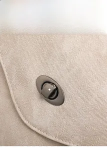 Detail of elegant gunmetal oval twist lock on beige striped corduroy travel backpack
