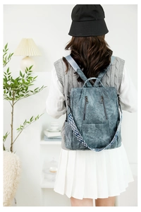 Close-up of vintage blue-grey backpack with ethnic woven strap worn by a model