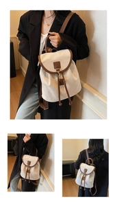 Detail view of beige canvas backpack with brown leather trim and drawstring buckle closure