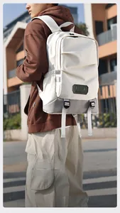 Detail of white travel backpack showing contrast grey base and front zip pocket
