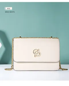 Détail de la surface en cuir blanc cassé avec logo doré et bandoulière en chaîne chic