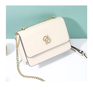Détail du sac crème avec boucle à anneaux dorés et bandoulière en chaîne et similicuir