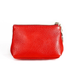 Detail of red pebbled leather coin purse with golden zipper closure and keychain ring