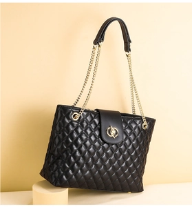 Detail einer schwarzen gesteppten Ledertasche mit goldener Kette und Ringschnalle