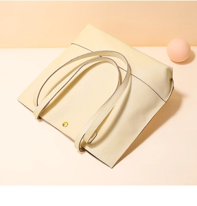 Vue détaillée du sac cabas en cuir crème avec grain litchi et boucle dorée élégante