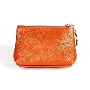 Macro shot of orange pebble leather coin purse with gold zipper and key ring detail