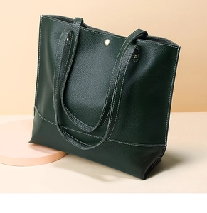 Détail d'un sac cabas en cuir vert foncé avec grain litchi et surpiqûres blanches