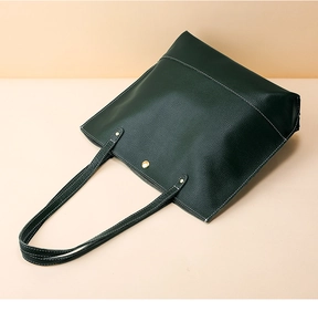 Détail du sac cabas en cuir vert foncé avec surpiqûres blanches et boucle dorée