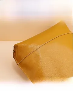Gros plan sur le grain du cuir gingembre et les coutures blanches précises du sac à main
