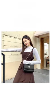 Gros plan du sac en cuir de vache noir avec logo doré et bandoulière en chaîne métal