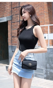 Detail of the elegant black mini crossbody bag with a round gold swivel lock and chain