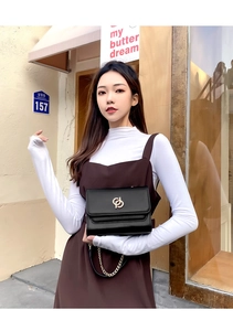 Détail du sac à bandoulière en cuir noir avec ferrures dorées et bandoulière chaîne