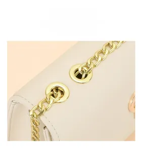 Détail de la chaîne en métal doré d'un sac bandoulière beige à la texture lisse et fine