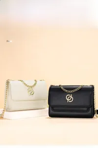 Détail de sacs à bandoulière blanc et noir avec logo doré entrelacé et bandoulière chaîne