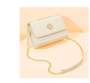 Détail du sac à rabat en similicuir blanc cassé avec logo doré et bandoulière chaîne