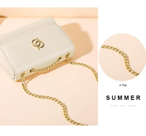 Détails d'un sac bandoulière en cuir blanc crème avec chaîne dorée et logo métallique
