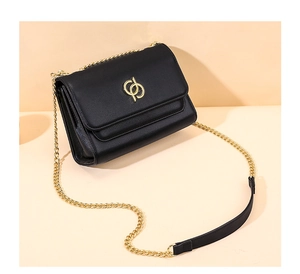 Détail d'un sac bandoulière en cuir noir avec logo doré et bandoulière en chaîne
