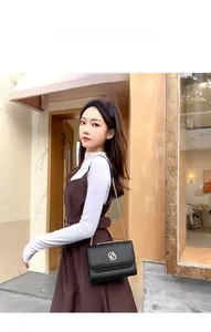 Vue extérieure d'un sac à rabat en cuir noir avec chaîne dorée et boucle en métal