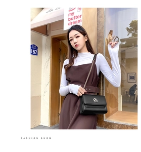 Vue détaillée du sac bandoulière en cuir noir avec chaîne dorée et boucle logo métallique