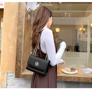 Détail d'un sac bandoulière chic en cuir PU noir avec logo doré et bandoulière chaîne