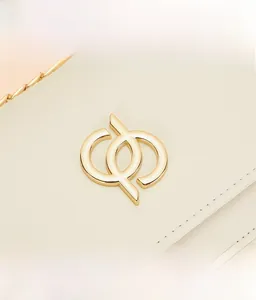 Détail du sac à bandoulière en cuir crème avec boucle dorée et surpiqûres de précision