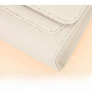 Gros plan des doubles surpiqûres sur le bord d'un sac bandoulière en cuir blanc crème