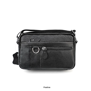 Detailed view of black pebbled leather crossbody bag with silver hardware and zip pockets