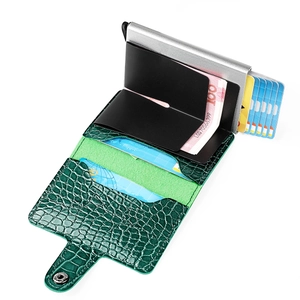 Detail of green crocodile texture wallet showing metal pop-up card case and cash pocket