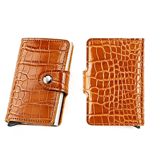 Macro view of brown crocodile-textured leather card holder with metallic buckle and slim slot