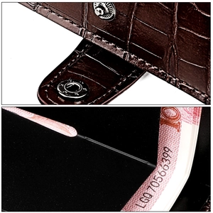 Macro detail of brown crocodile embossed wallet showing metal snap and interior slots