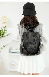 Detail of vintage black leather backpack featuring stylish geometric patterned shoulder strap