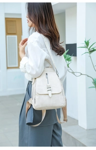 Outdoor shot of minimalist cream canvas backpack with vertical zip and brown wide straps