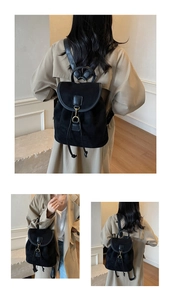 Detail of matte black backpack featuring gold hardware lock and drawstring closure