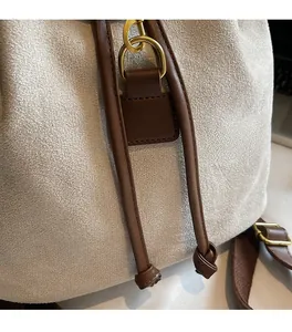 Close-up of beige frosted suede texture with brown leather accents and gold hardware