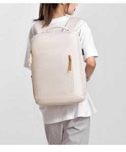 Detail of light beige backpack with vertical zipper, leather pull, and USB charging port