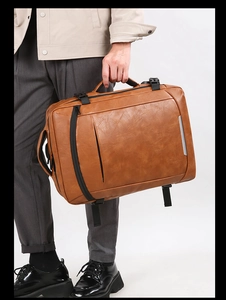 Brown leather laptop backpack with dual carry handles and silver reflective safety strip
