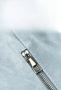 Detail shot of silver metal zipper on light blue canvas backpack with textured fabric
