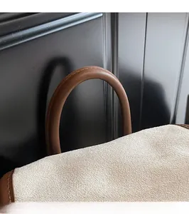 Detail of round brown leather handle with premium stitching on a beige frosted backpack