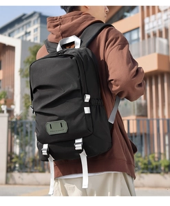 Detail of black backpack featuring a rubber patch and modern pleated design on front