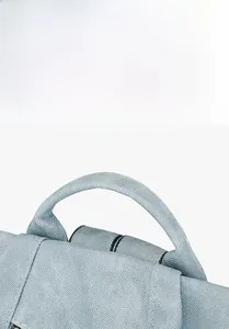 Close-up of the thick reinforced top handle on a light blue twill fabric backpack