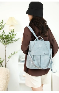 Dettaglio dello zaino in pelle azzurra con spallacci decorativi in stile etnico