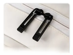 Detail view of durable black metal double zippers on a white travel backpack