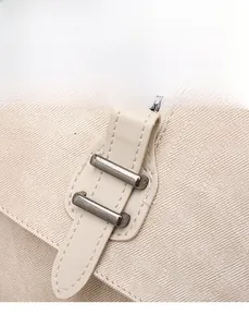 Close-up of vintage silver buckle and high-density twill canvas texture on a cream backpack
