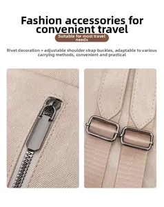 Detail of gunmetal zippers and adjustable shoulder buckle on beige canvas backpack