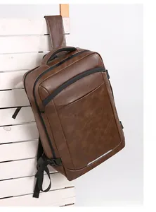 Detailed view of brown PU leather business backpack with metal zippers on white fence