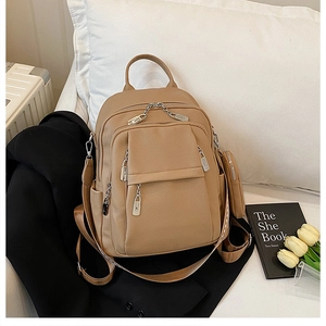 Detail view of khaki pebbled leather backpack with multiple zip pockets and mini pouch