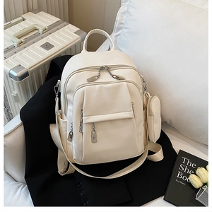 Detail shot of a cream lychee leather backpack with silver hardware on a black suit blazer