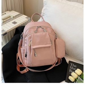 Detail of pink pebbled leather backpack with silver hardware on a black blazer background